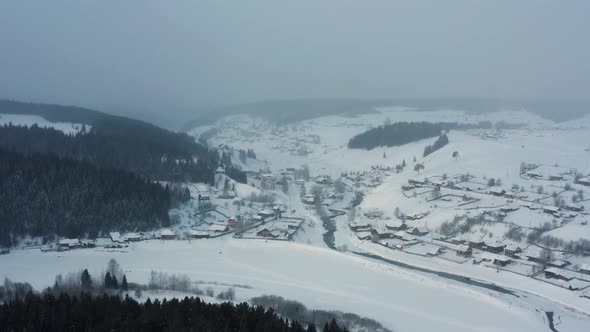 Aerial View of a Village in the Snow on the Bank of a Frozen River