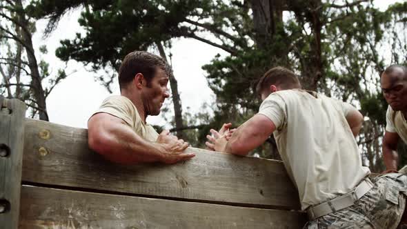 Male soldiers assisting their team mate to climb a wooden wall 4k