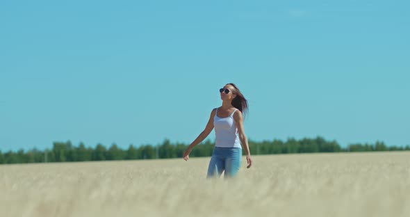 Happy and Beautiful Girl Walks Across the Field and Smiles