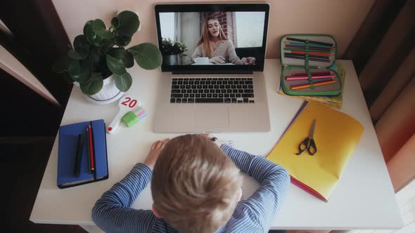 Online lesson at home. Kid boy study with teacher on video chat using laptop. E-learning class.