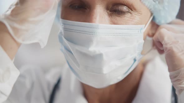 Close Up Portrait of Senior Female Doctor Putting of Medical Mask and Smiling at Camera