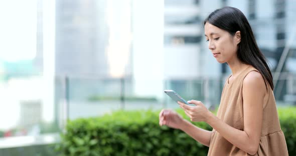 Woman using smart phone and sitting on city park