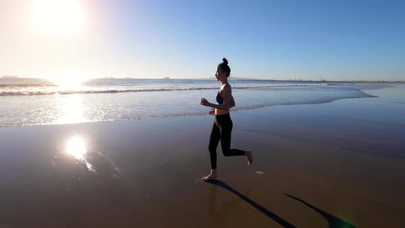 Slow motion shot of an Asian woman jogging on the beach