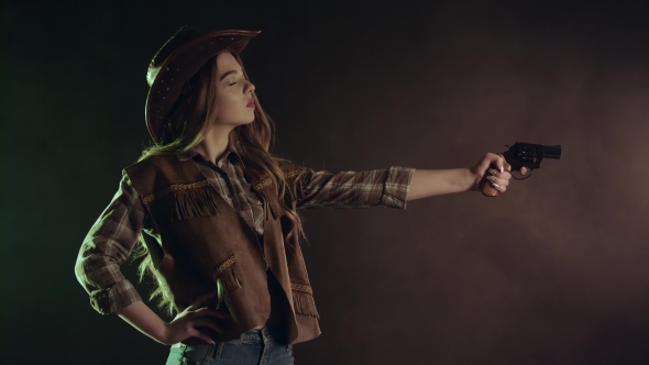 Cowboy Girl Is Aiming and Making a Shot. Black Smoke Background.