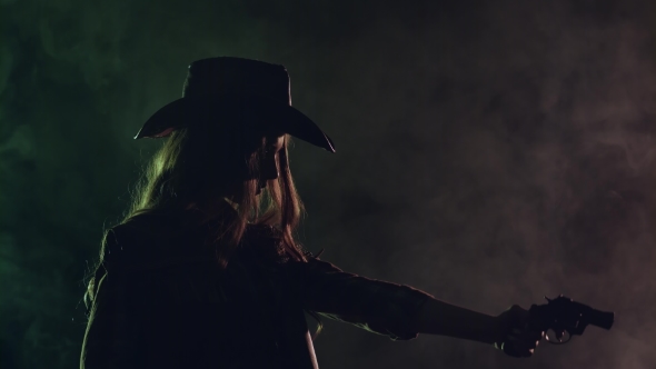 Cowgirl Holds a Revolver in Her Hands and Aiming at the Villain. Black Smoke Background. . Side View