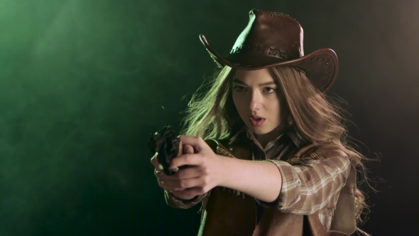 Cowgirl Holds a Revolver in Her Hands and Aiming at the Villain. Black Smoke Background.