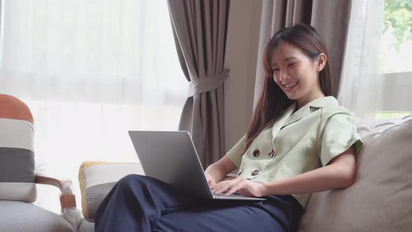 Happy young asian woman using laptop to video call or facetime to talk with customer or friend