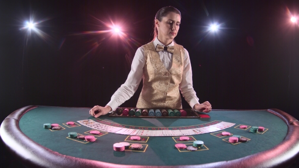 Casino Dealer Woman Shuffles the Poker Cards and Performing Trick with Cards. Black Background.