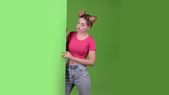 Teen Peeks Out From Behind a Green Board and Shows a Thumbs Down. Green Screen