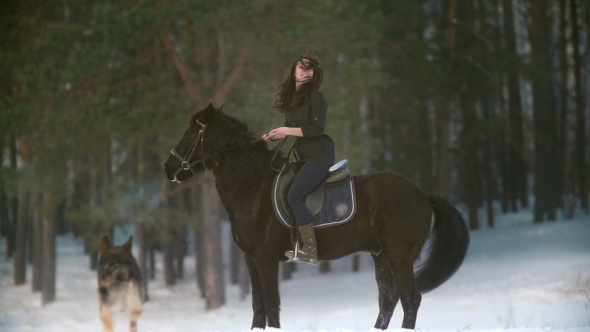 Professional Beautiful Longhaired Woman Riding a Black Horse Through the Deep Snow in the Forest