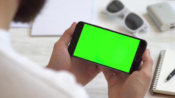 Black Smartphone Horizontally with Green Screen for Chroma Key Compositing the Hands of a Man