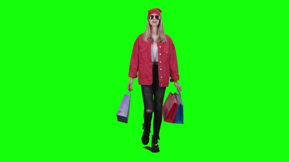 Teenager in Glasses Goes Shopping, Holding Packages in His Hands. Green Screen