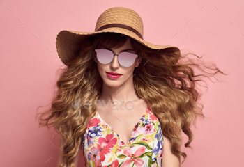 ion Young woman in Hat and Sunglasses. Portrait Glamour Beautiful Model with Trendy Stylish curly hairstyle. Spring Summer Lady on Pink