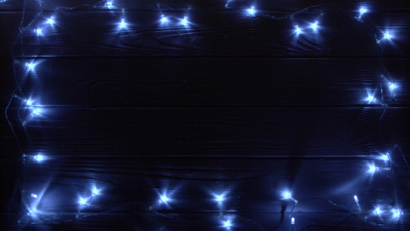 Christmas Garland Burns Bright Light Lying on a Table in a Dark Room. Top View