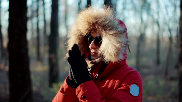 Woman In Parka Warming His Cold Hands In Winter Day. Holiday Vacation Trip In Winter Forest. Gloves