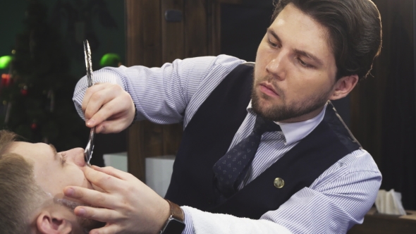 Professional Barber Shaving His Client with a Razor