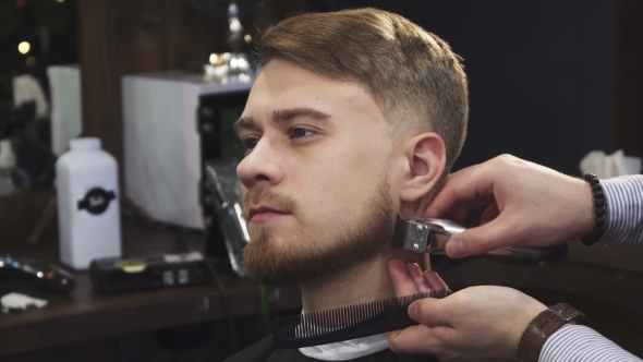 Young Handsome Man Getting His Beard Trimmed By a Professional Barber
