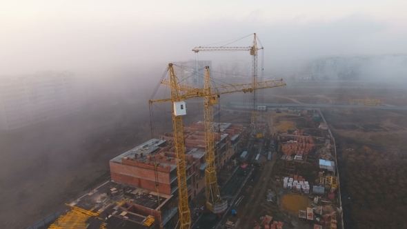 Construction Site in the Fog with a Bird's Eye with Tower Cranes on the Sunset