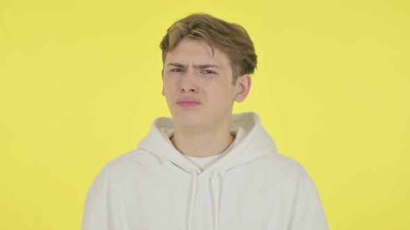 Disappointed Young Man Reacting Loss on Yellow Background