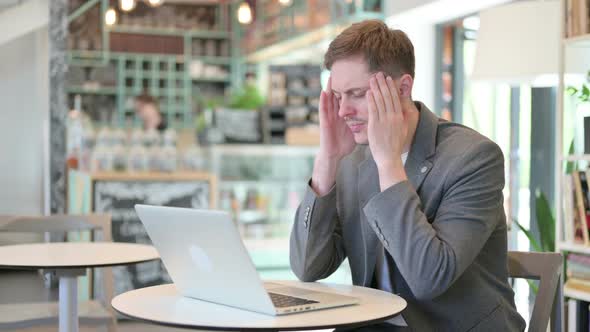 Young Man with Laptop Having Headache