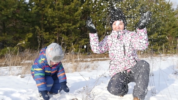 Happy Woman and Little Boy Playing with Snow in the Winter Forest