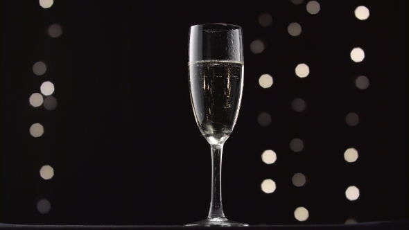 Chilled Glass of Champagne. Bokeh Blinking Black Background