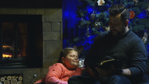 Man Reading Christmas Story To Daughter