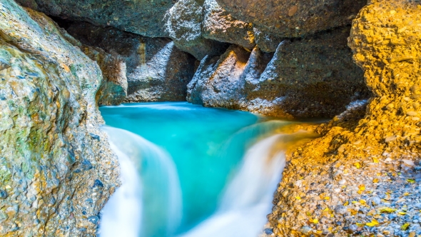 Colorful Waterfall and a Lake in a Cave in the Mountains of Central Asia