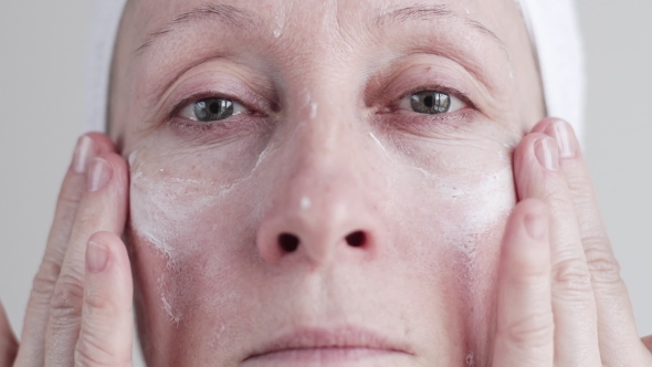 Caucasian Mid Age Woman Applying Cream To Her Face.