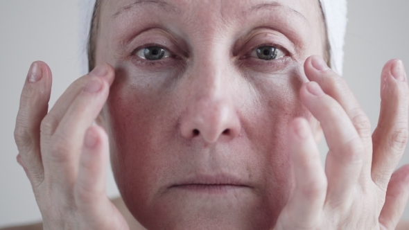 Caucasian Mid Age Woman Applying Cream To Her Face.