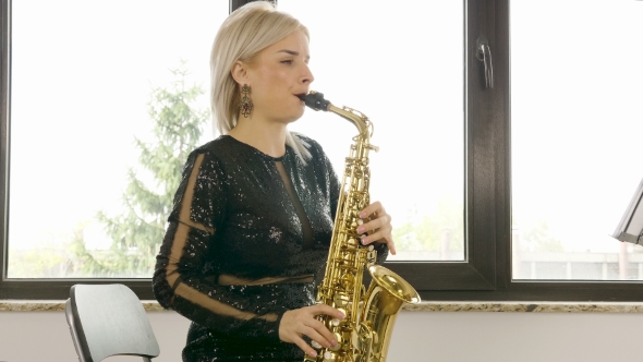 Beautiful Saxophonist Woman Playing at the Sax in the Living Room