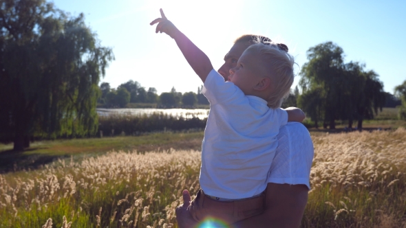 Young Dad Holding His Child on Hands at the Meadow