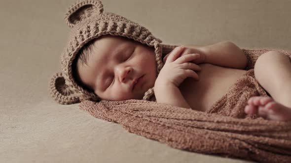 Newborn baby sleeping peacefully with checkered cloth on brown background