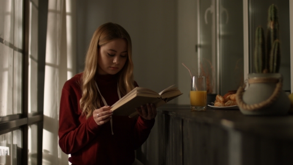 Intelligent Young Woman Reading a Book at Home