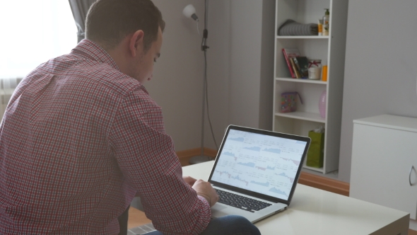 Man in Works From Home Using the Top and Trackpad. Young Business Man Sitting at Table Drinking