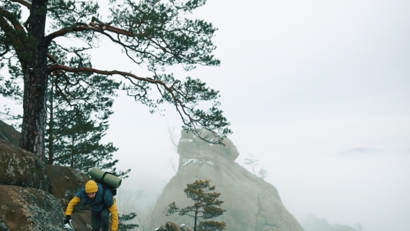 Man in Yellow Jacket Climbs the Rocks in the Winter Mountains