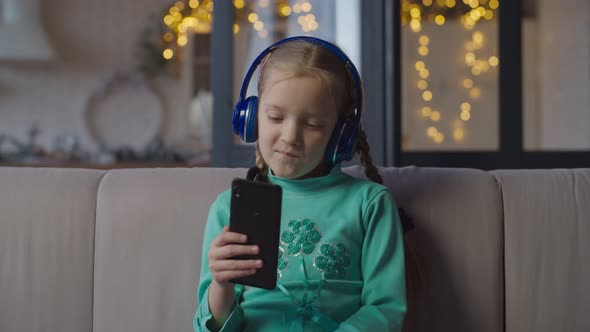 Girl in Headphones Listening To Music on Cellphone