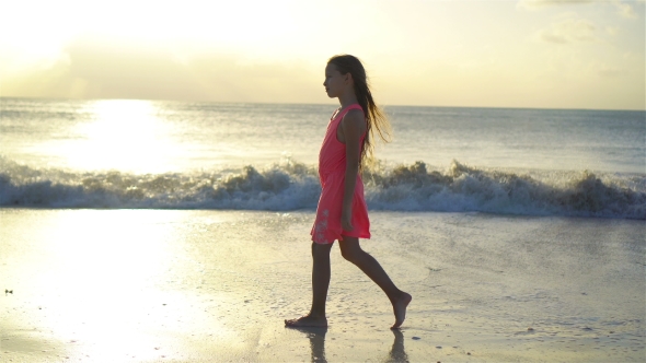 Sihouette of Little Girl Walking on the Beach at Sunset.