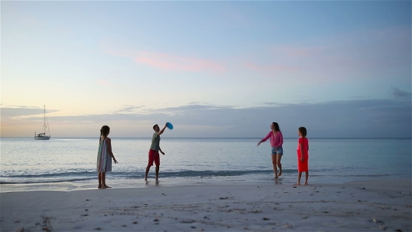 Happy Family Playing with Flying Disk at Beach at Sunset