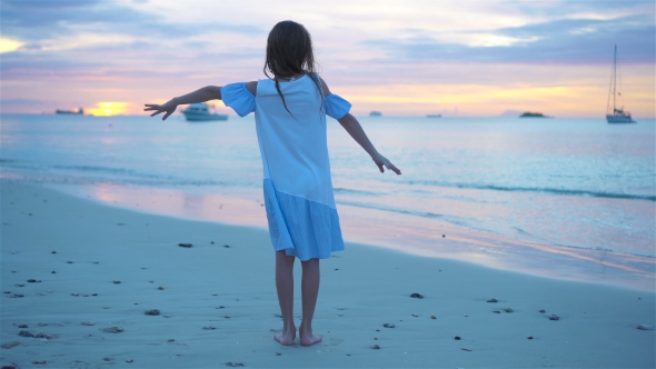 Sihouette of Little Girl Dancing on the Beach at Sunset.