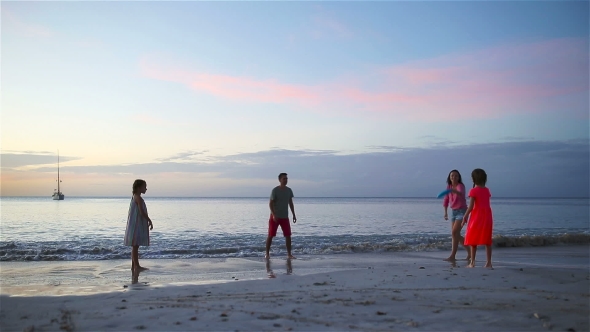 Happy Family Playing with Flying Disk at Beach at Sunset