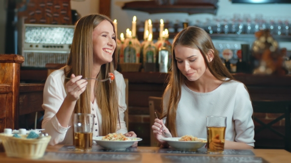 Two Smiling Young Women Having Lunch in the Restaurant
