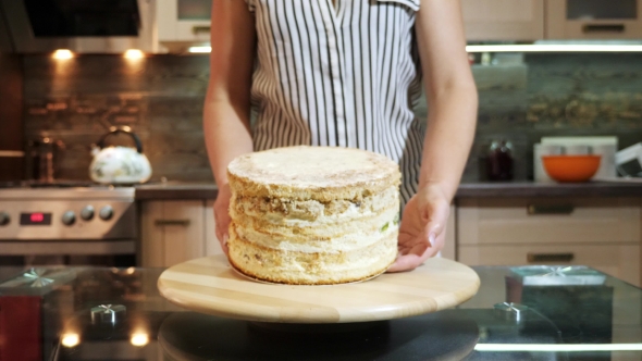 Woman Put Cake on a Rotating Stand, Preparing To Decorate a Cake