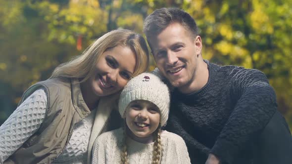 Happy Young Family With Beautiful Daughter Posing for Camera in Autumn Forest