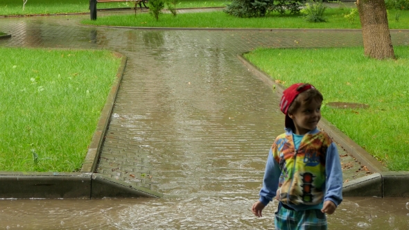 The Boy Runs through the Puddle in the Rain