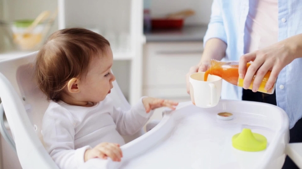 Happy Mother with Spoon Feeding Baby at Home 1