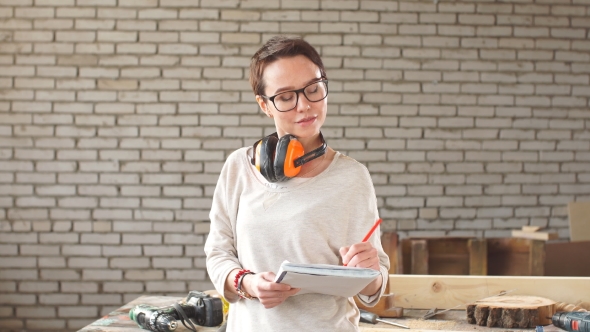 Happy Attractive Hardworking Professional Female Worker with Pen and Tablet in Workshop.