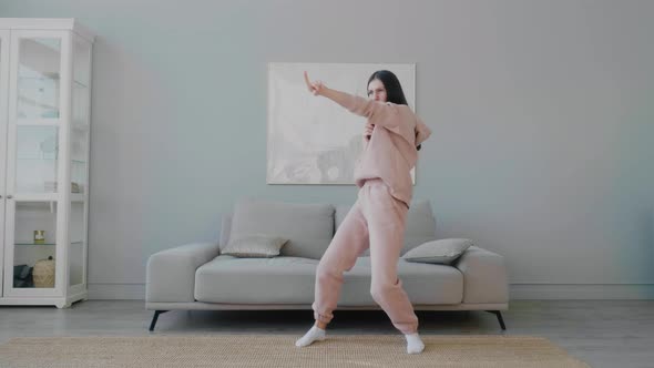 A young Caucasian woman with glasses having fun, dancing, singing songs with a remote control.