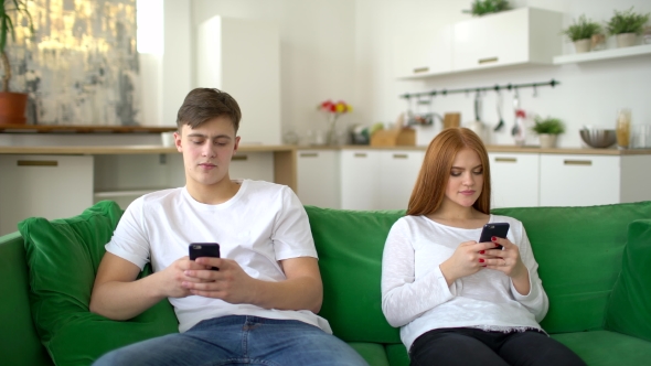 Man and Woman Ignoring Each Other in Their Mobile Phones in Their Home During the Morning.
