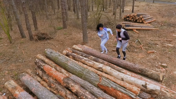 Young People Runs on the Logs in the Forest